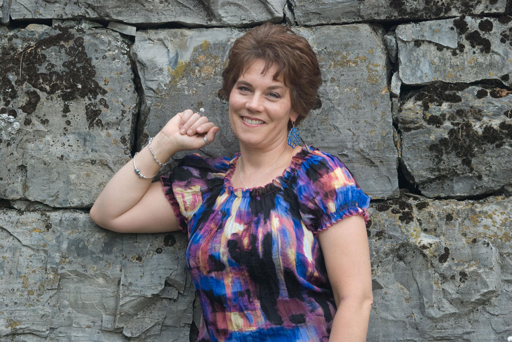 Jill Hatter smiling in front of a stone wall